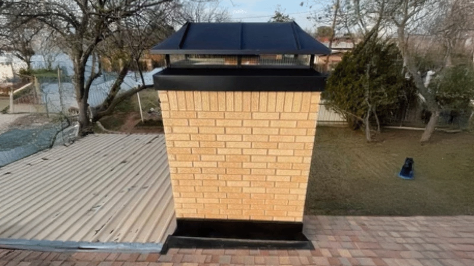 Existing Chimney4u project photograph showing a large black metal top assembly installed over a brick chimney